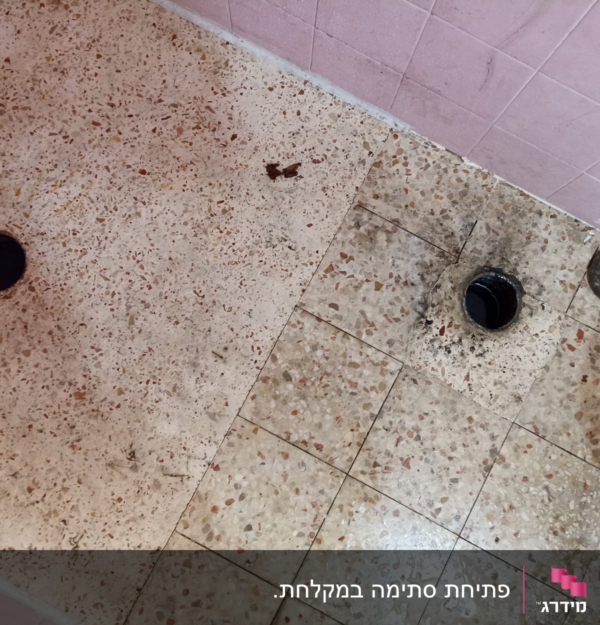 רצפת חדר אמבטיה עם חור ניקוז פתוח ופקק שחור